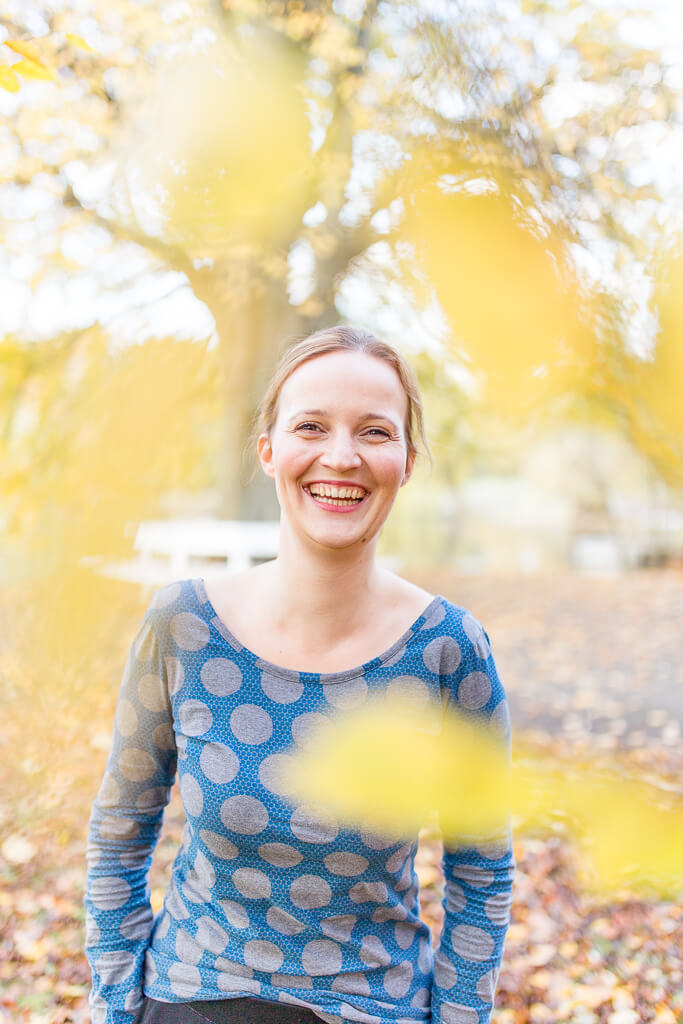 Frau im Herbst, lacht in Kamera