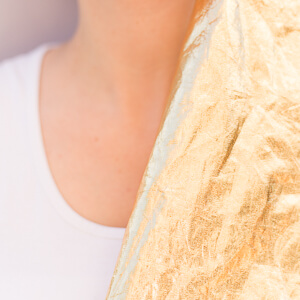Goldene Folie an Haut mit weißen T-Shirt